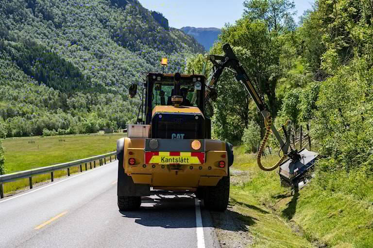 Foto av traktor som gjennomfører kantslått langs veg.